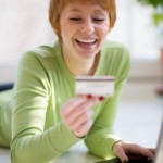 Smiling young woman shopping online with credit card and laptop computer