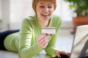 Smiling young woman shopping online with credit card and laptop computer